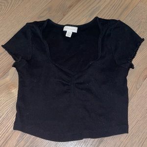 Cropped black T-shirt with a sinched neckline and partly ruffled sleeves.